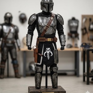 May include: A full Mandalorian armor suit, featuring a silver helmet, chest plate, and arm guards. The suit includes a black undersuit, brown belt with ammunition, and a holster. The armor is displayed on a wooden base with the text "BESKAR FORGE".