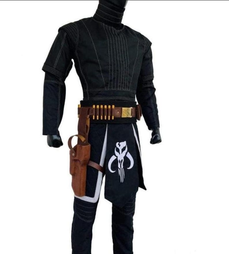 May include: Black costume with a high collar, long sleeves, and a decorative stitched design. The costume includes a brown belt with gold accents and a holster. A black and white graphic is on the front of the costume.