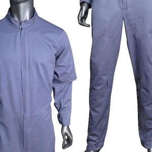 K&ouml;nnte beinhalten: Ein hellblauer Overall mit Stehkragen, verdecktem Frontrei&szlig;verschluss und langen &Auml;rmeln. Das Kleidungsst&uuml;ck umfasst eine gerade geschnittene Hose mit sichtbaren rechteckigen Steppn&auml;hten an den Oberschenkeln und Unterschenkeln, pr&auml;sentiert an einer Schaufensterpuppe.