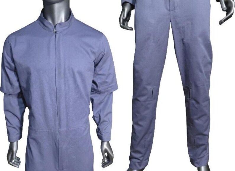K&ouml;nnte beinhalten: Ein hellblauer Overall mit Stehkragen, verdecktem Frontrei&szlig;verschluss und langen &Auml;rmeln. Das Kleidungsst&uuml;ck umfasst eine gerade geschnittene Hose mit sichtbaren rechteckigen Steppn&auml;hten an den Oberschenkeln und Unterschenkeln, pr&auml;sentiert an einer Schaufensterpuppe.