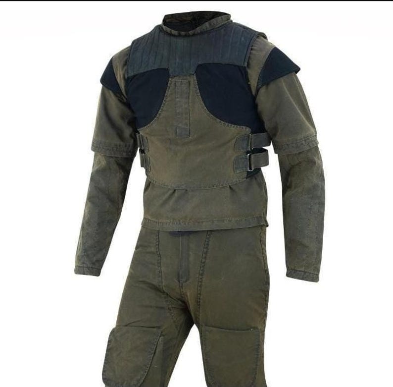 May include: A two-piece olive green outfit consisting of a long-sleeved top and matching trousers. The top features a dark charcoal chest panel with vertical stitching, short sleeves over long sleeves, and adjustable side straps with metal buckles.