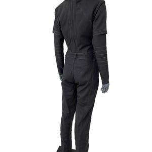 May include: A black long-sleeved jumpsuit featuring a high collar, structured shoulders, and visible white topstitching along the seams. The garment includes a fitted bodice, a defined waistline with belt loops, and straight-leg trousers.