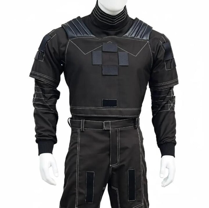 K&ouml;nnte beinhalten: Schwarzes taktisches Outfit mit wei&szlig;en Steppn&auml;hten. Das Outfit besteht aus einem hochgeschlossenen Oberteil mit Schulterakzenten und kurzem Bund, kombiniert mit einer passenden Hose. Das Design hat mehrere quadratische Patches und einen G&uuml;rtel.