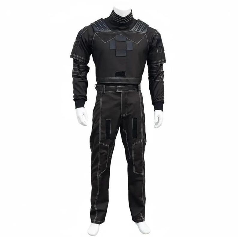 K&ouml;nnte beinhalten: Ein schwarzer Overall mit wei&szlig;en N&auml;hten, der auf einer Schaufensterpuppe pr&auml;sentiert wird. Das Outfit hat einen hohen Kragen, lange &Auml;rmel und ein kurzes Oberteil. Die Hose hat ein gerades Bein-Design. Der Overall hat eine taktische oder futuristische &Auml;sthetik.