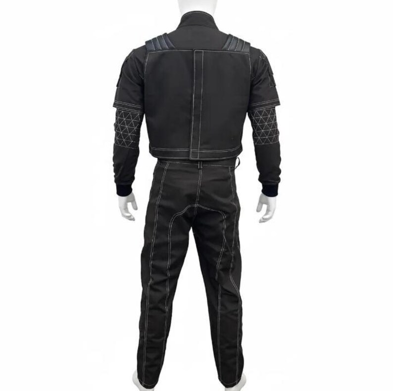 K&ouml;nnte beinhalten: Schwarzes zweiteiliges Outfit mit wei&szlig;en N&auml;hten. Die Jacke hat einen hohen Kragen und geometrische Muster an den &Auml;rmeln. Die Hose hat ein gerades Bein-Design. Das Outfit wird auf einer Schaufensterpuppe pr&auml;sentiert.