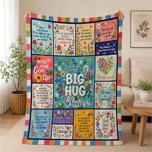 May include: A multi-colored crochet-bordered throw blanket featuring a grid of floral panels with inspirational text including "Sending you a BIG HUG Claire," "Never ever give up," "Believe in yourself," and "Be kind to yourself."