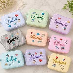May include: A collection of nine rectangular, zippered pouches in various pastel colors, each featuring embroidered names and small medical-themed icons like hearts, pills, stethoscopes, and clipboards on a subtle pinstriped fabric surface.