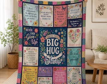 May include: A multi-colored patchwork-style throw blanket featuring various floral-bordered panels with inspirational text, including the central message "Sending you a big hug" with the name "Olivia" and illustrated arms.