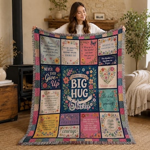 May include: A woven throw blanket featuring a grid of colorful floral panels with inspirational text, including the central phrase 'Sending you a big hug Olivia'. The blanket has a fringed edge and a multi-colored checkered border pattern.