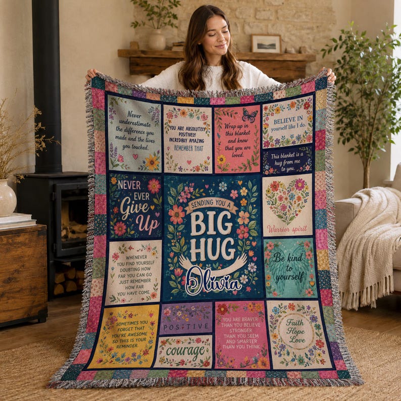 May include: A woven throw blanket featuring a grid of colorful floral panels with inspirational text, including the central phrase 'Sending you a big hug Olivia'. The blanket has a fringed edge and a multi-colored checkered border pattern.