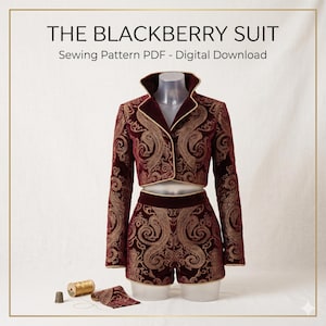 Puede incluir: THE BLACKBERRY SUIT Sewing Pattern PDF - Digital Download. Un conjunto de chaqueta corta y pantalones cortos en terciopelo burdeos oscuro con patrones de volutas doradas y ribetes dorados. Incluye un dedal de metal y un carrete de hilo dorado.