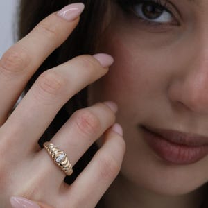 May include: A white ceramic mug with a black handle and the text "But First, Coffee" in a bold, black font. The mug is set against a blurred background, suggesting a cozy setting.