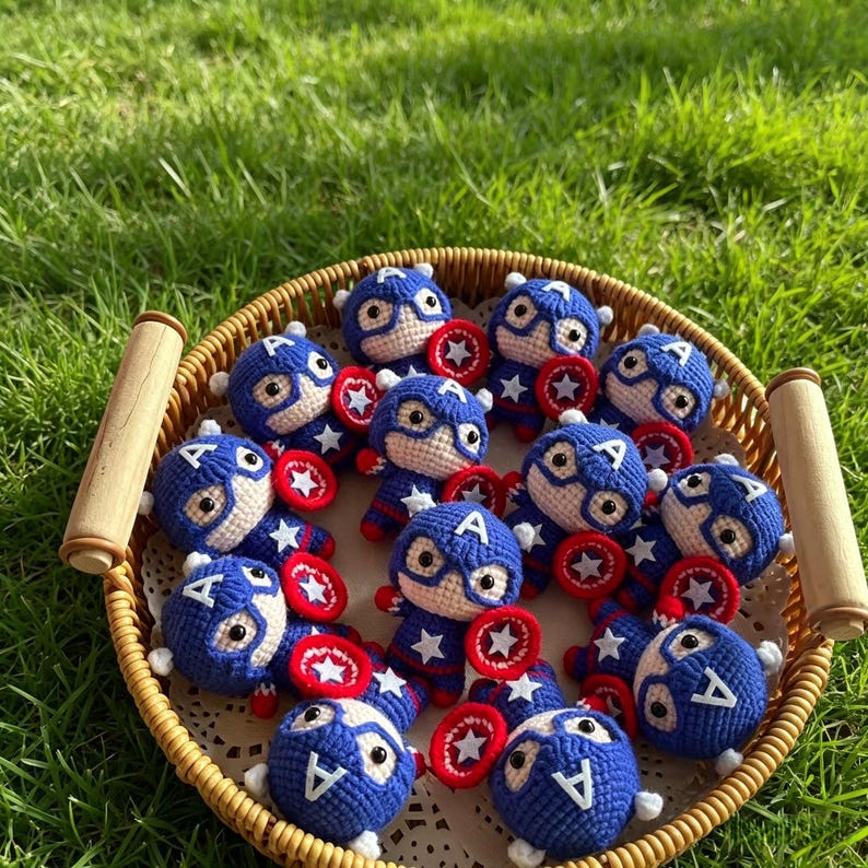 Basket full of many tiny crochet star shield hero dolls with red and blue shields displayed on green grass in the sunlight