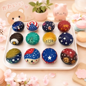May include: A collection of twelve decorative balls with various designs, including the American flag, a rocket ship, and the Statue of Liberty. Some balls feature the numbers "250" and "1776". The balls are arranged on a white tray.
