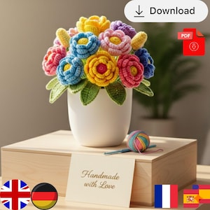 Könnte beinhalten: Ein farbenfroher Häkelblumenstrauß in einem weißen Topf. Die Blumen sind in verschiedenen Farben, darunter Gelb, Blau, Rosa und Lila. Ein Knäuel Garn und eine Häkelnadel liegen neben dem Strauß. Eine Karte trägt die Aufschrift "Handmade with Love."