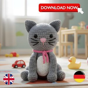 Könnte beinhalten: Eine graue gehäkelte Katzendoll mit einer rosa Nase und einem rosa Schal. Die Katze hat schwarze Schnurrhaare und große schwarze Augen. Die Puppe sitzt auf einem gemusterten Teppich. Ein rotes Auto und eine gelbe Ente befinden sich im Hintergrund. Der Text "DOWNLOAD NOW" steht in einem roten Banner.