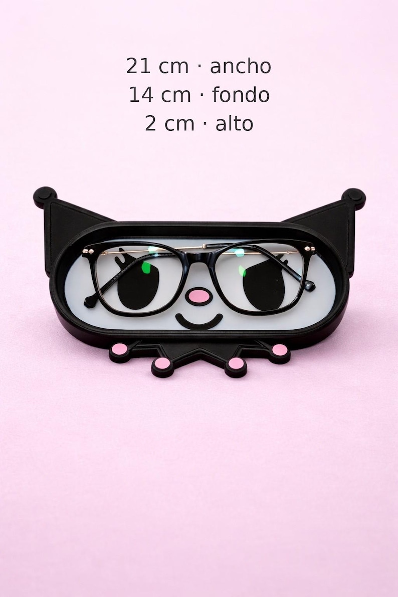 May include: A black eyeglasses holder shaped like a cartoon character's face, with a white interior and pink accents. The holder contains a pair of black-framed glasses. Dimensions are 8.3 inches wide, 5.5 inches deep, and 0.8 inches high.