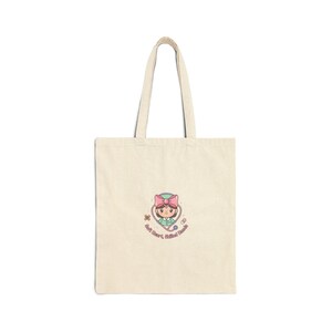 May include: A cream-coloured tote bag with a cartoon nurse wearing a pink bow and holding a stethoscope. The text "Soft Heart, Skilled Hands" is printed below the illustration. The bag has two long handles.