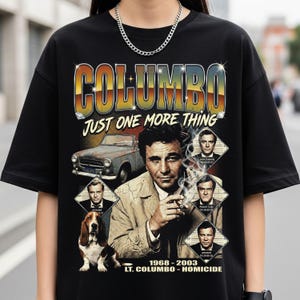 May include: Black t-shirt featuring a graphic design with the word "COLUMBO" in a retro font. The design includes an image of a car, a dog, and several portraits of actors. The text "JUST ONE MORE THING" is also included.