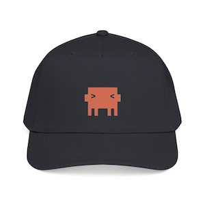 May include: A dark charcoal grey baseball cap featuring a centred, coral-coloured pixelated graphic of a square-shaped character with two small arms and a face composed of two simple chevron-style eyes pointing inward toward the centre.