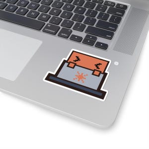May include: A pixel art sticker featuring a laptop with a light grey base and a dark grey keyboard area. The screen is orange with two black bracket symbols and a central orange starburst icon, all outlined in a thick dark brown border.