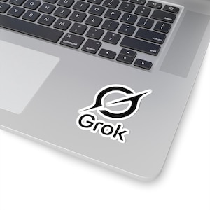 Peut inclure: Un autocollant blanc avec le mot "Grok" en gras et arrondi. L'autocollant présente un graphisme noir et blanc d'une forme de "S" stylisée avec une ligne qui le traverse, placé sur un ordinateur portable argenté.