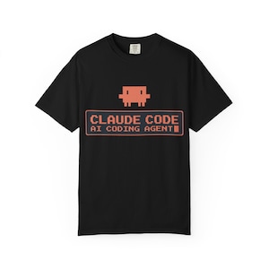 Puede incluir: Camiseta negra con un gráfico naranja pixelado de una criatura sobre el texto "CLAUDE CODE AI CODING AGENT" en una fuente retro. El diseño está centrado en la parte delantera de la camiseta.