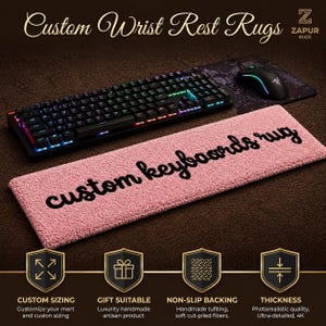 Könnte beinhalten: Eine rechteckige, rosafarbene Handgelenkauflage mit texturierter, getufteter Oberfläche und dem schwarzen Schriftzug custom keyboards rug in der Mitte. Die Auflage liegt vor einer schwarzen mechanischen Tastatur und einer Computermaus.