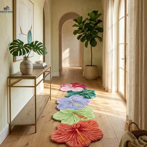 May include: A hallway with a series of colorful, flower-shaped rugs in shades of red, green, purple, and pink. The rugs are arranged in a line on a wooden floor. The hallway also features a gold-framed table and a large potted plant.