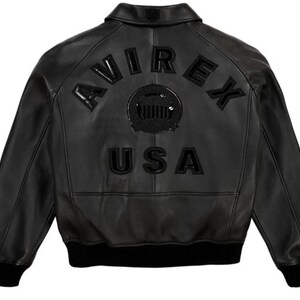 May include: Black leather bomber jacket with the word "AVIREX" arched across the back, above a circular emblem and the word "USA". The jacket has a ribbed collar, cuffs, and hem.