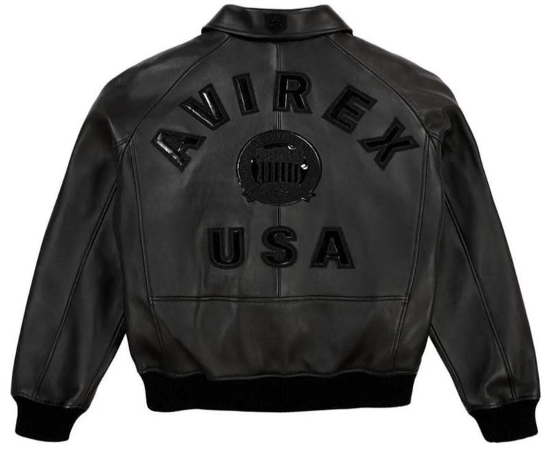 May include: Black leather bomber jacket with the word "AVIREX" arched across the back, above a circular emblem and the word "USA". The jacket has a ribbed collar, cuffs, and hem.