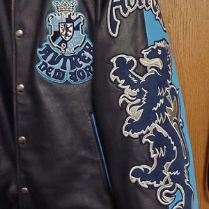 Peut inclure: Une tasse en c&eacute;ramique blanche avec une anse noire et le texte "But First, Coffee" en gras noir. La tasse est pos&eacute;e sur un fond neutre, soulignant son design simple.