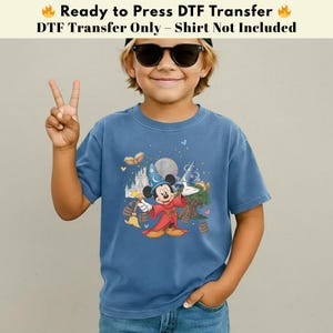 Pode incluir: Camiseta azul com um desenho do Mickey Mouse vestido de mago, com um castelo e elementos m&aacute;gicos. O texto na parte superior diz "Ready to Press DTF Transfer" e "DTF Transfer Only - Shirt Not Included".