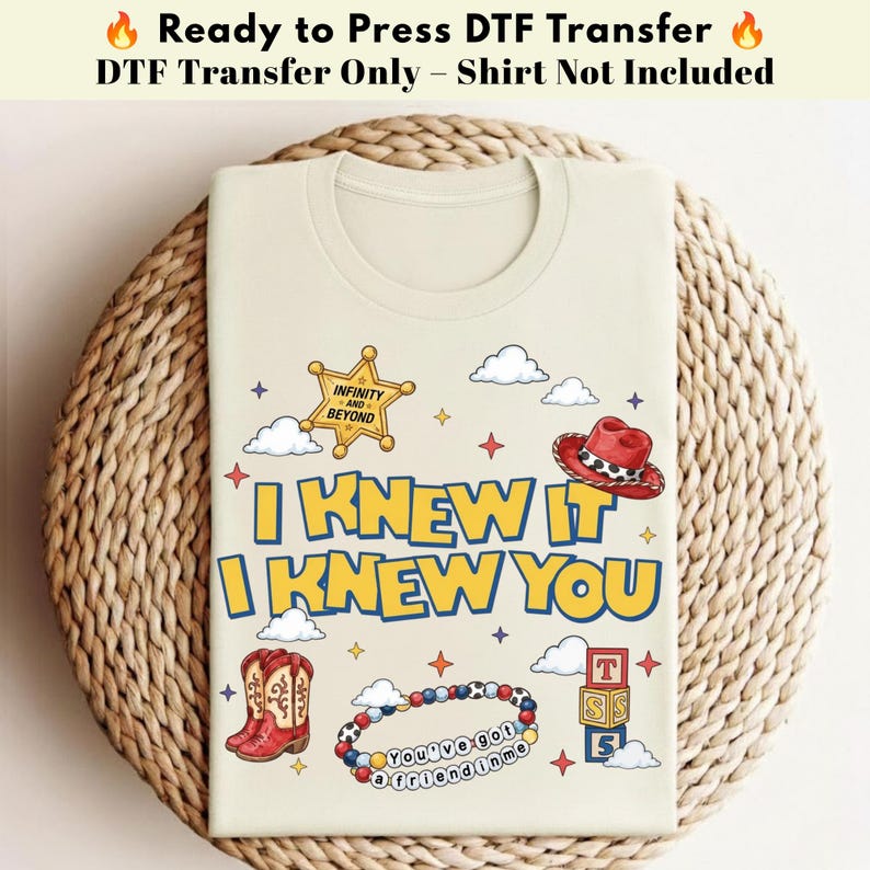 May include: A cream-colored DTF transfer featuring the text I KNEW IT I KNEW YOU in blue and yellow. Graphics include a gold sheriff badge with INFINITY AND BEYOND, a red cowboy hat, red cowboy boots, a colorful beaded bracelet, and alphabet blocks.