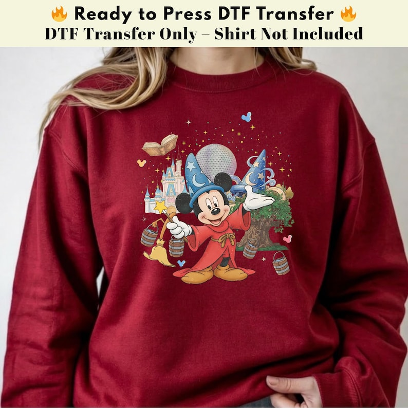Pode incluir: Um moletom bord&ocirc; com um gr&aacute;fico colorido do Mickey Mouse vestido de mago, segurando uma varinha. O gr&aacute;fico inclui um castelo, um globo e outros elementos m&aacute;gicos. O texto na parte superior diz "Ready to Press DTF Transfer".