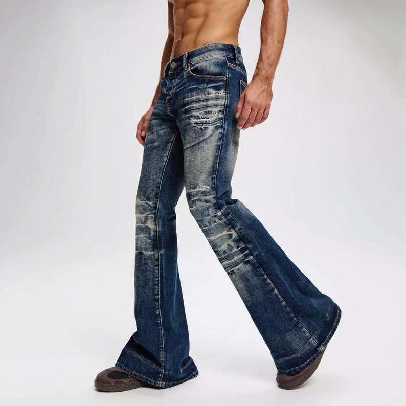 Op de afbeelding: Donkerblauwe denim jeans met een uitlopend pijp ontwerp. De jeans hebben distressed details op de dijen en knie&euml;n, en een klassiek vijf-zakken ontwerp. De jeans worden gedragen met bruine schoenen.