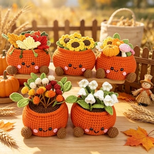 May include: Five round, orange, crocheted pots with smiling faces and small brown feet, each containing different crocheted plants including sunflowers, pumpkins, mushrooms, and white flowers, arranged on a wooden surface.