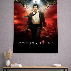 May include: A tapestry featuring the movie poster for "Constantine." The image shows a man in a suit with angel wings, holding a cross. The background is a fiery red with the movie title at the bottom.