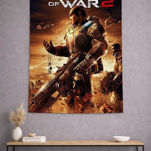Puede incluir: Un tapiz con el videojuego Gears of War 2. La obra muestra a un soldado con una armadura detallada, sosteniendo un arma grande, con una escena de campo de batalla en el fondo. El título se muestra en la parte superior.