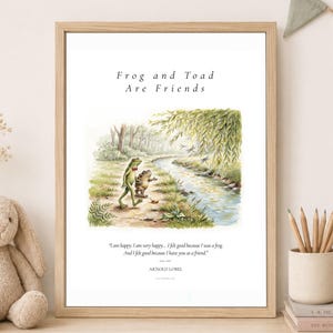 May include: A framed wall art print featuring a watercolour illustration of a frog and a toad walking by a stream. The text reads: Frog and Toad Are Friends, and: I am happy. I am very happy... I felt good because I was a frog. And I felt good because I have you as a friend. ARNOLD LOBEL.