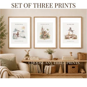 May include: A set of three framed wall art prints featuring watercolor illustrations of a child walking, a rabbit in a garden, and a cow jumping over the moon. Each print includes text captions. The prints are displayed in light wood frames.