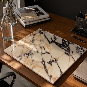 May include: A rectangular marble board featuring a polished surface with a cream-coloured base and prominent, dark brown and black veining patterns. The board has a flat, smooth top and straight, clean edges, showcasing natural stone variations.