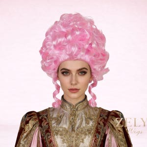 May include: A pink, curly wig with a bouffant style, reminiscent of historical fashion. The wig features a voluminous top and two long, curled tendrils framing the face. The model is wearing a detailed, ornate costume. The ZELYA Wigs logo is visible.