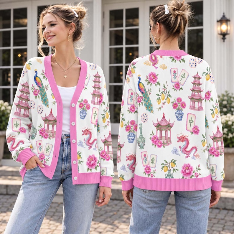 May include: A white long-sleeve button-down cardigan featuring a pink trim and a repeating pattern of colorful peacocks, pagodas, dragons, floral arrangements, and mahjong tiles. The knit garment has a V-neckline and ribbed cuffs and hem.