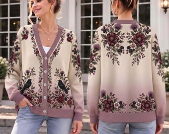 May include: A beige and mauve gradient cardigan featuring a V-neckline, button-down front, and long sleeves. The knit fabric displays a detailed botanical print of dark red flowers, purple thistles, and black birds on the front and back.