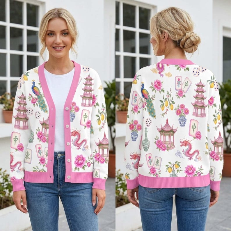 May include: A white V-neck cardigan with a pink trim and button closure, featuring a repeating print of pink pagodas, dragons, peacocks, mahjong tiles, and floral arrangements. The long-sleeved knit garment has a ribbed hem and cuffs.