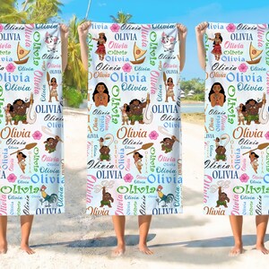 May include: A white beach towel featuring a repeating pattern of the name Olivia in various fonts and colors, interspersed with colorful illustrations of characters, a boat, a rooster, and tropical flowers across the entire fabric surface.