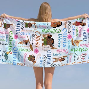 May include: A white beach towel featuring a repeating pattern of the name Olivia in various colors and fonts, interspersed with cartoon illustrations of characters, a sailboat, and pink hibiscus flowers against a light blue gradient background.