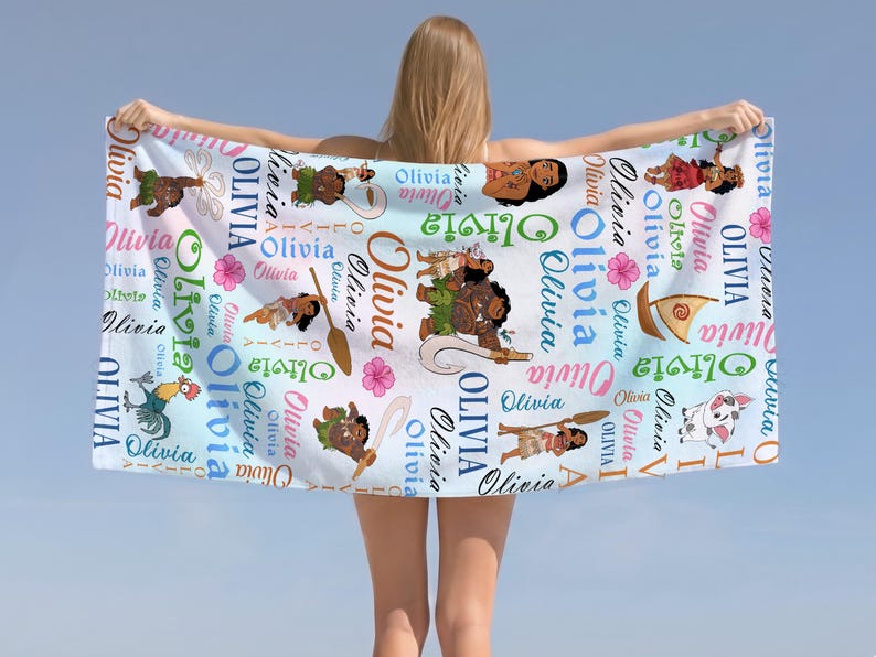 May include: A white beach towel featuring a repeating pattern of the name Olivia in various colors and fonts, interspersed with cartoon illustrations of characters, a sailboat, and pink hibiscus flowers against a light blue gradient background.