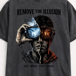 May include: Dark gray t-shirt with a graphic design featuring a split face wearing VR goggles. The left side shows a cityscape, the right side a fiery scene. Text reads "REMOVE THE ILLUSION" and "SEE WHAT THEY HIDE".